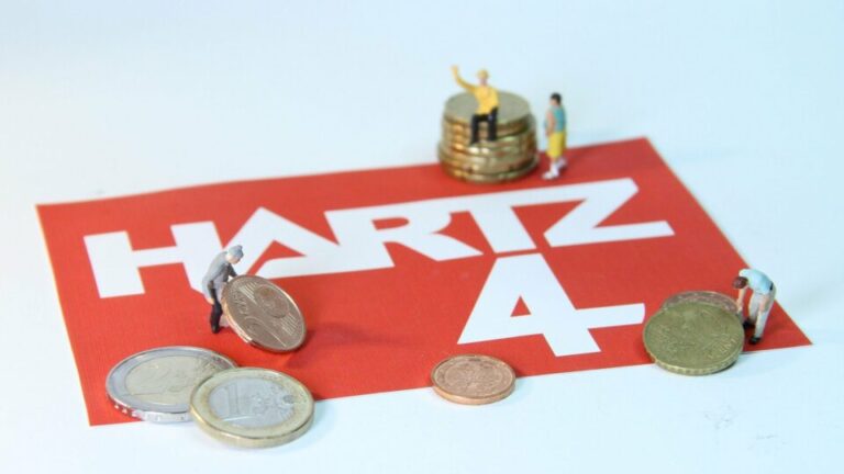 Roter Aufkleber mit der Aufschrift Harz4, ein paar Euromünzen und kleinen Modellbaufiguren