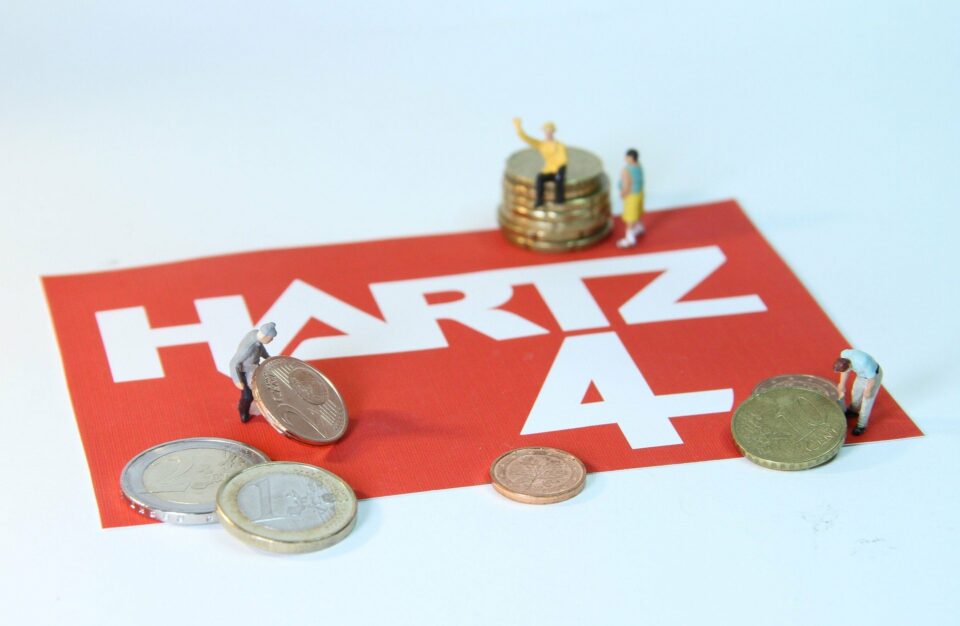 Roter Aufkleber mit der Aufschrift Harz4, ein paar Euromünzen und kleinen Modellbaufiguren