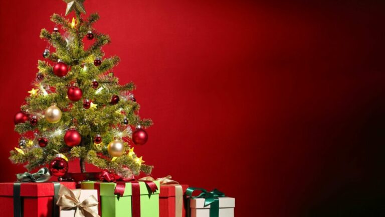 Weihnachtsbaum mit Geschenken vor einer roten Wand
