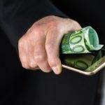 Hand hält Handy und einen 100€ Schein