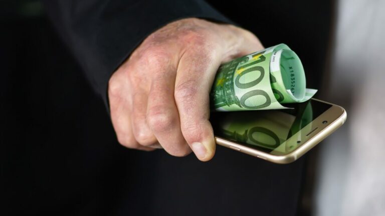 Hand hält Handy und einen 100€ Schein