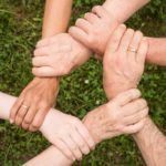 & Hände greifen sich an Handgelenke was einen Kreis ergibt