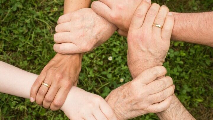 & Hände greifen sich an Handgelenke was einen Kreis ergibt