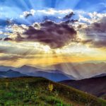 Naturbewusstsein Jugendliche Studie Bild einer Bergwiese auf Bergpanorame. Die Sonne strahlt hinter einer Wolke