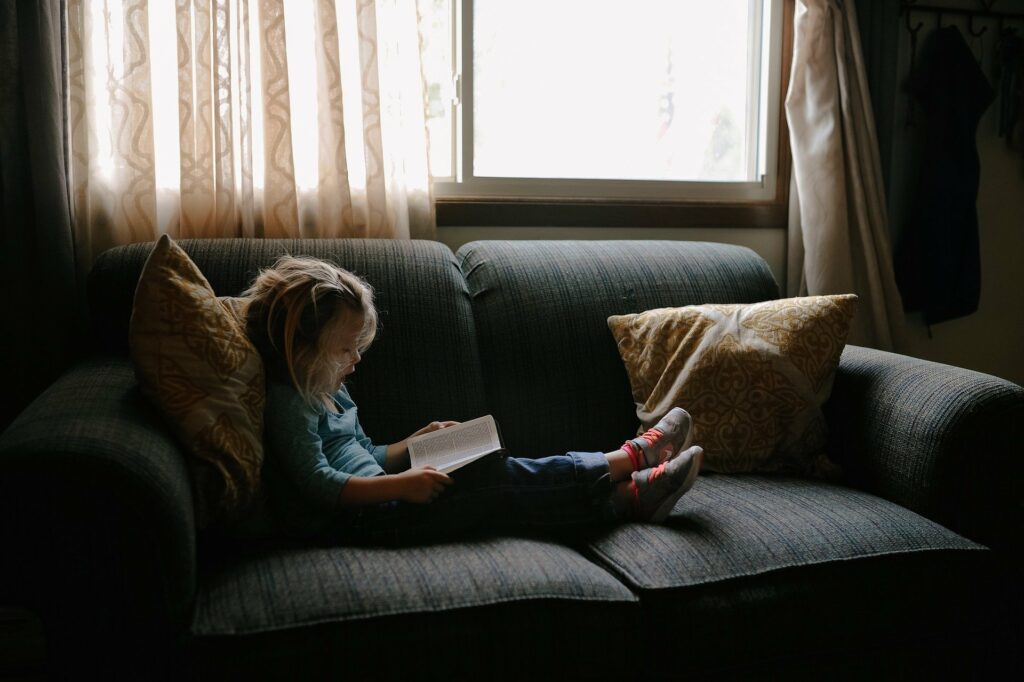 Kind mit Buch auf der Couch