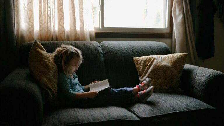 Kind mit Buch auf der Couch