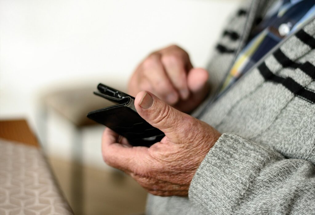 Alter Mann hält Smartphone in seiner Hand