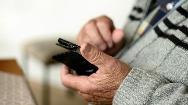 Alter Mann hält Smartphone in seiner Hand