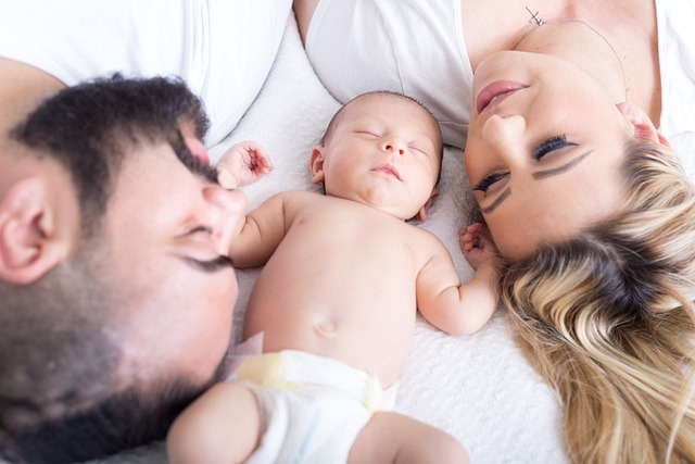 Familie Kopf an Kopf. Dazwischen ein Baby.