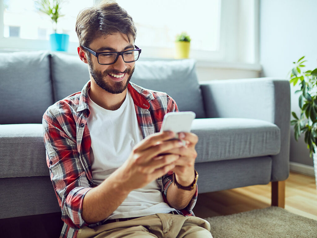 Junger Kerl lachend am Smartphone