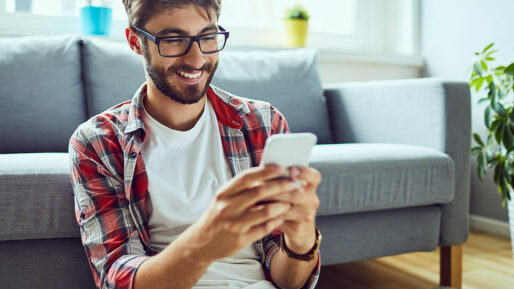 Junger Kerl lachend am Smartphone