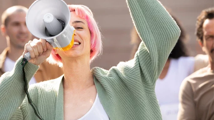 Frau mit pinken Haaren spricht durch ein Megafon