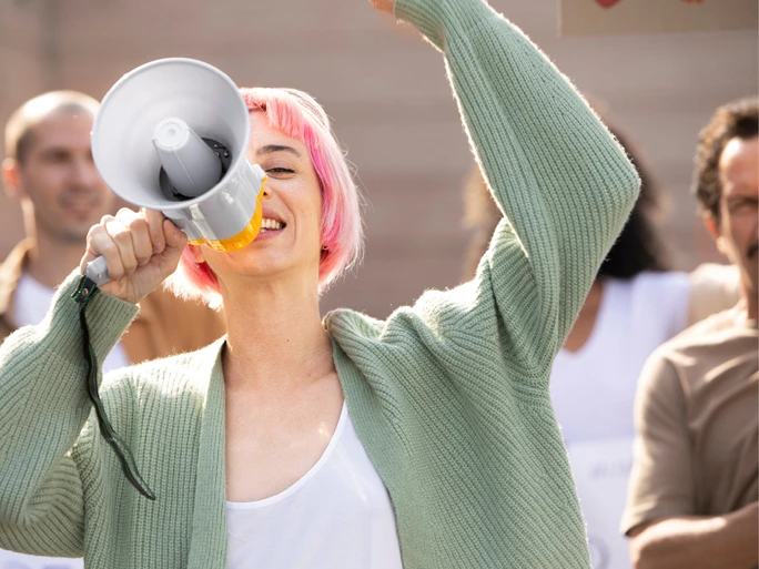 Frau mit pinken Haaren spricht durch ein Megafon