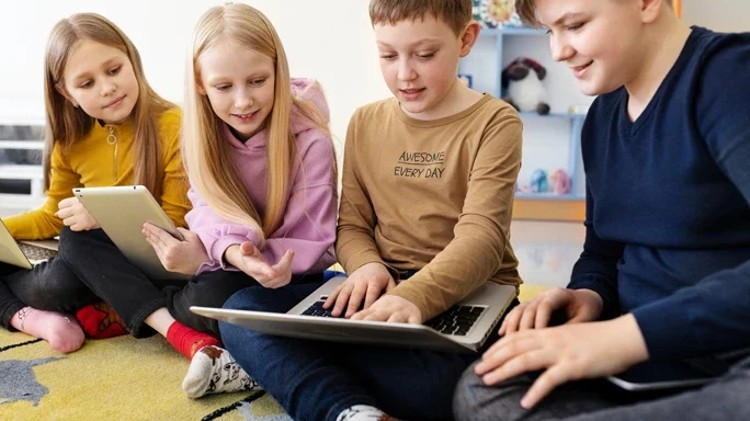 Vier Kinder betrachten etwas in einem Laptop