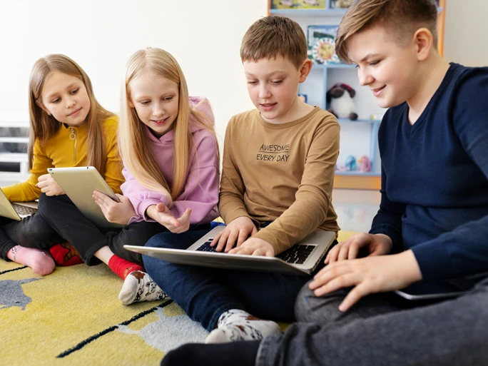 Vier Kinder betrachten etwas in einem Laptop