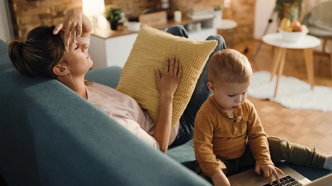 Getsresste Mutter auf Couch. Daneben ihr Kind am Laptop.