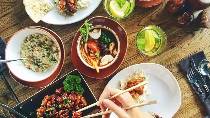 Asiatisches Essen. Eine Hand hält Stäbchen.