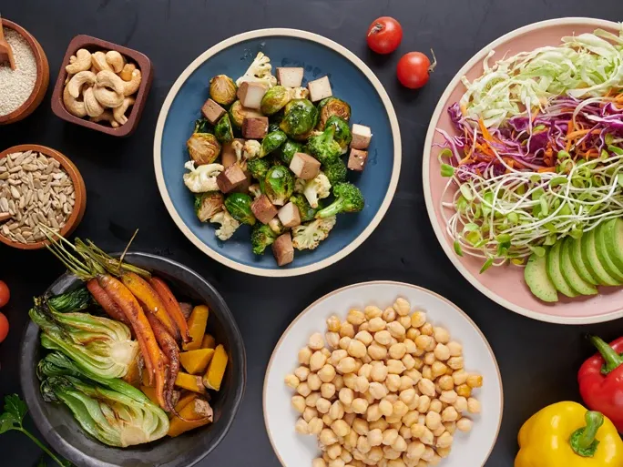 Ein Tisch mit gesunden veganen Produkten auf Tellern und Schüsseln