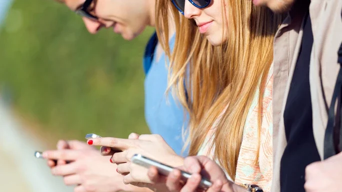 Drei Personen mit Sonnenbrille und Smartphones stehen in einer Reihe und spielen mit dem Handy.