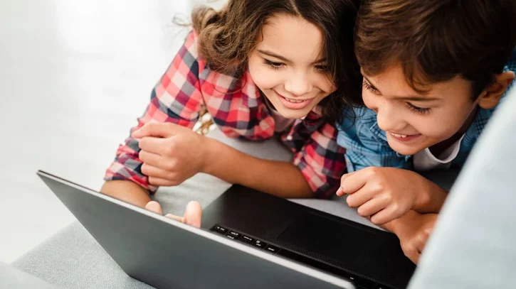 Junge und Mädchen sehen sie etwas auf einem Laptop an und haben Spaß dabei.