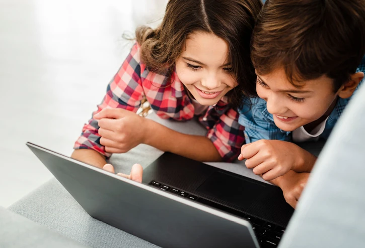 Junge und Mädchen sehen sie etwas auf einem Laptop an und haben Spaß dabei.