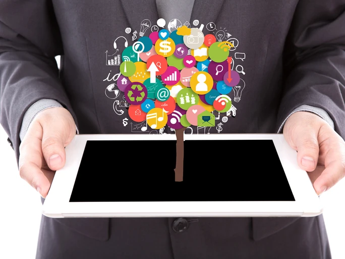 Massenkommunikationstrends Ein Mann hält ein Tablet, aus dem diverse Icons als Baum symbolisiert sind.
