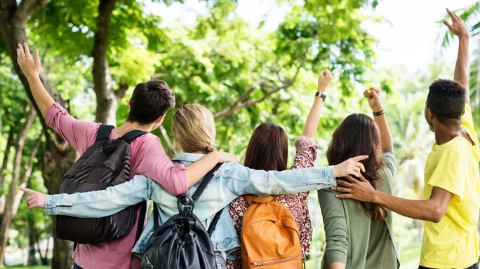 5 Personen in einem Park, vier strecken die Arme in die Luft
