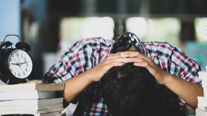 Symbolbild für den TK-Gesundheitsreport 2023. Es zeigt einen erschöpften Studenten.
