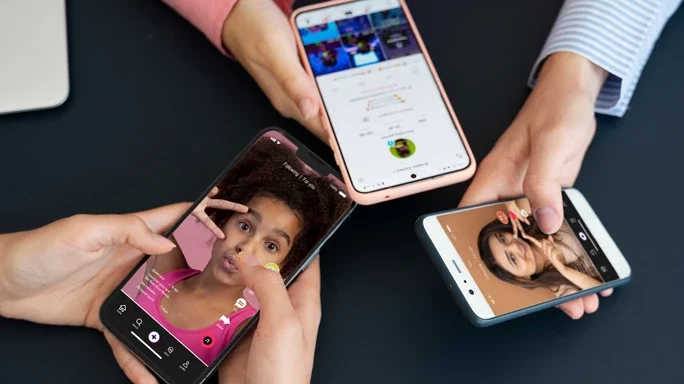 Informationsquelle TikTok - Drei Personen halten ihr Smartphone aneinander