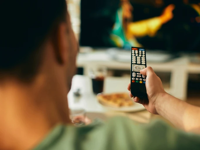 werbungtv Mann sitzt auf Couch mit Fernbedienung in der Hand