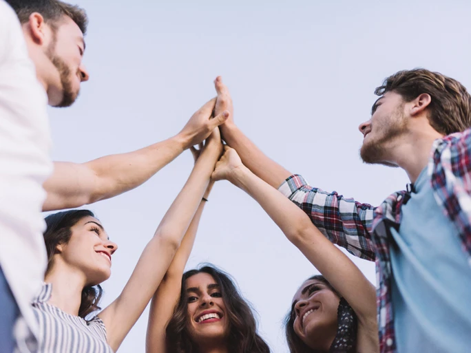 Jugendliche in Deutschland. 5 Personen stehen im Kreis und geben sich alle ein High-Five.
