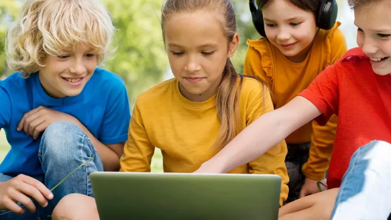 Kinder in bunten T-Shirts vor einem Laptop