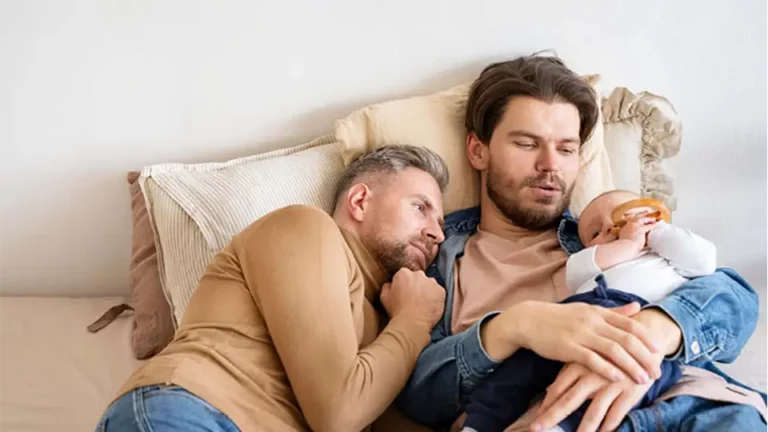 Männliches Paar mit Baby liegen im Bett