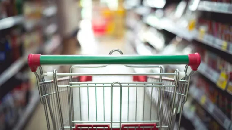 Blick über einen Einkaufswagen in einen Gang im Supermarkt