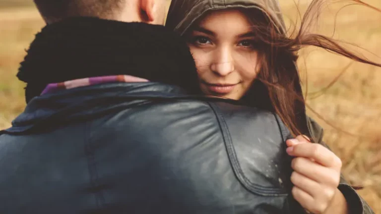 Teenager umarmen sich. Das Mädchen schaut in die Kamera.