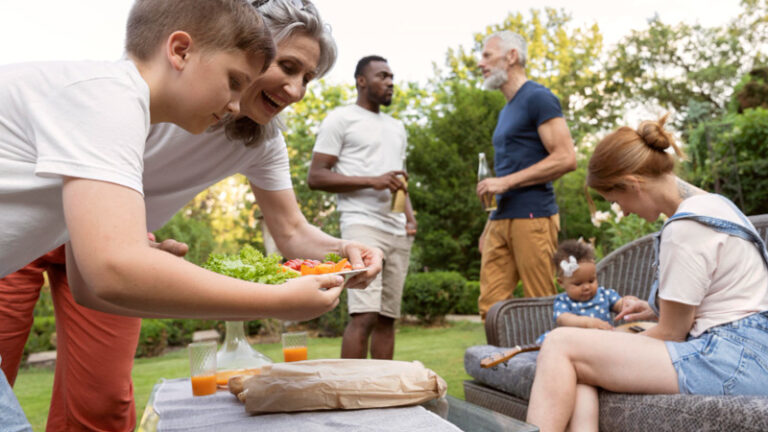 Ein Paar mit zwei Kindern zu Besuch bei den Eltern im Garten.