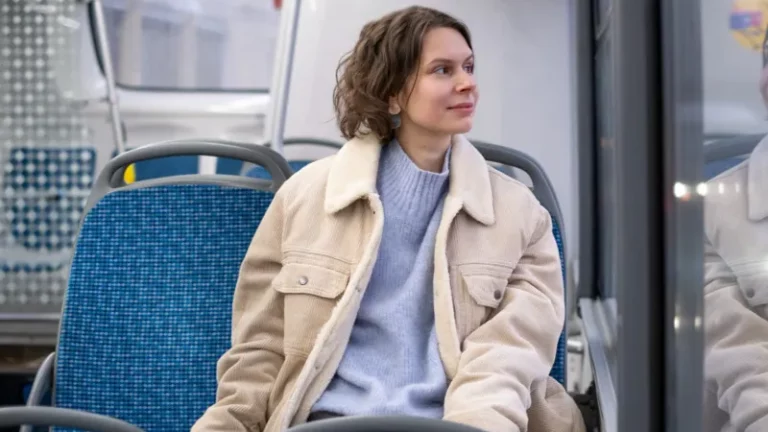 Frau in einem Stadtbus sieht zufrieden aus dem Fenster.