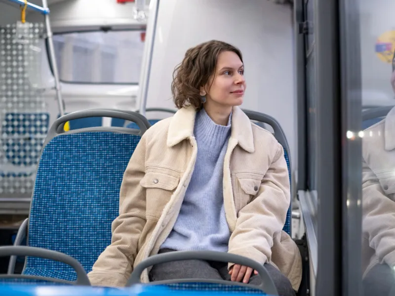 Frau in einem Stadtbus sieht zufrieden aus dem Fenster.