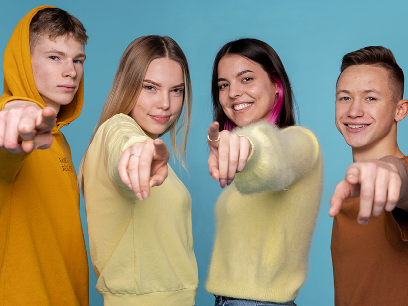Jugendliche zeigen mit dem Finger auf den Betrachter des Bildes.