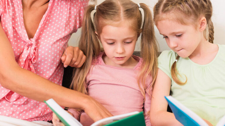 Mutter mit ihren zwei Töchtern, die Mädchen halten jeweils ein Buch in den Händen und lesen gespannt.