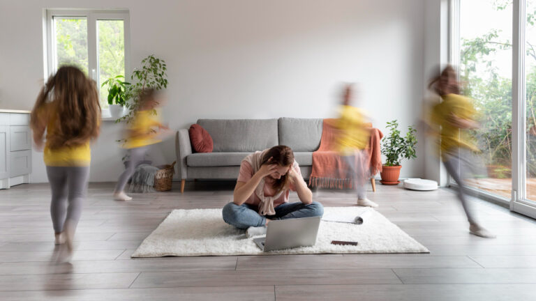 Familie im Wohnzimmer: Mutter arbeitet am Laptop, Kind rennt verschwommen vorbei.