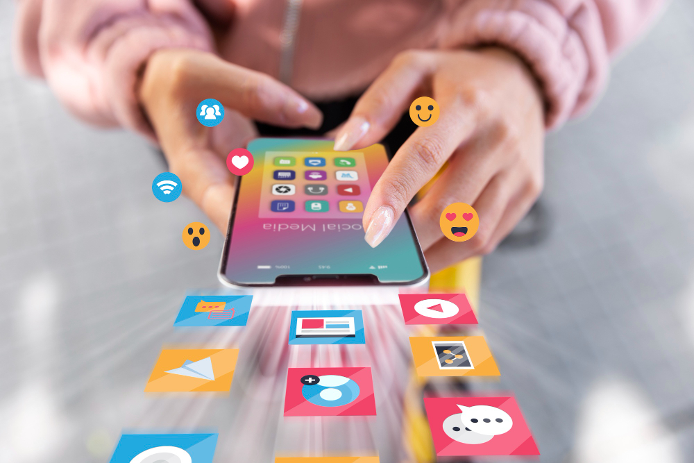 Hände tippen auf einem Smartphone, während Social-Media-Symbole und Emojis umher schweben.