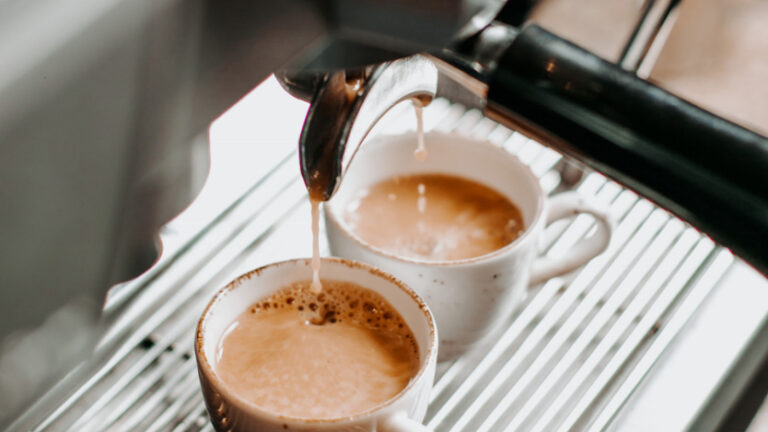 Zwei Tassen Kaffee werden aus einer Espressomaschine in Porzellantassen gebrüht.