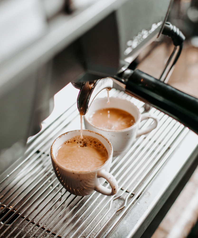 Zwei Tassen Kaffee werden aus einer Espressomaschine in Porzellantassen gebrüht.