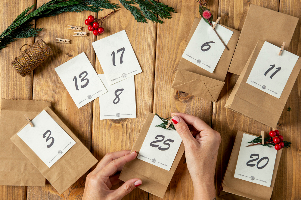Zwei Hände befestigen eine nummerierte Karte auf einer kleinen Papiertüte für einen Adventskalender.